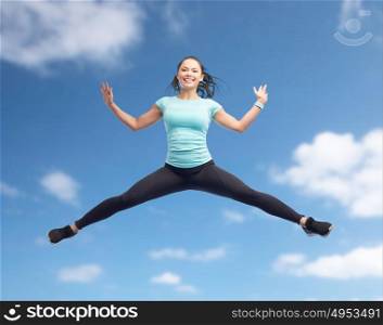 sport, fitness, motion and people concept - happy smiling young woman jumping in air over blue sky background. happy smiling sporty young woman jumping in air
