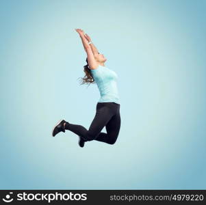 sport, fitness, motion and people concept - happy smiling young woman jumping in air or dancing over blue background. happy smiling sporty young woman jumping in air