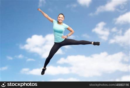 sport, fitness, motion and people concept - happy smiling young woman jumping in air over blue sky background. happy sporty young woman jumping in blue sky
