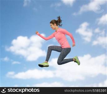 sport, fitness, motion and people concept - happy smiling young woman jumping in air over blue sky and clouds background. happy smiling sporty young woman jumping in sky