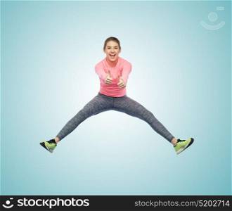 sport, fitness, motion and people concept - happy smiling young woman jumping in air over white background showing thumbs up. happy smiling sporty young woman jumping in air