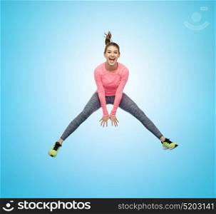 sport, fitness, motion and people concept - happy smiling young woman jumping in air over blue background. happy smiling sporty young woman jumping in air