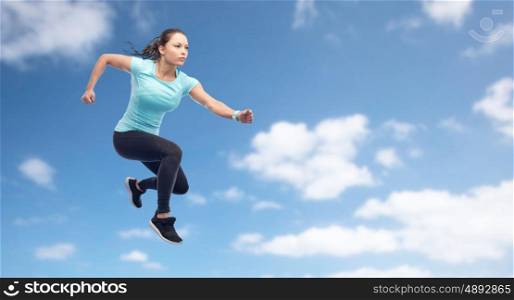 sport, fitness, motion and people concept - happy young woman jumping in air over blue sky and clouds background