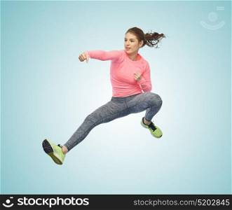 sport, fitness, motion and people concept - happy young woman jumping in air in fighting pose over white background. happy sporty young woman jumping in fighting pose