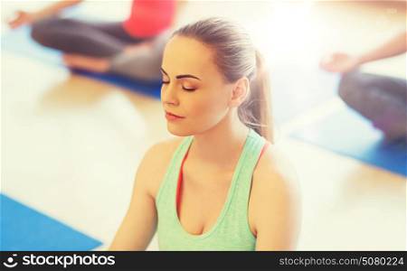 sport, fitness, people and healthy lifestyle concept - group of happy women exercising yoga and meditating in lotus pose in gym. young woman making yoga and meditating in gym