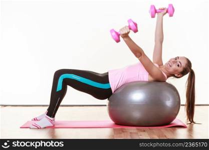 Sport, fitness, people, gym concept. Happy lady doing some workout. Beautiful girl has nice sporty outfit. . Sporty girl with pink dumbbells.