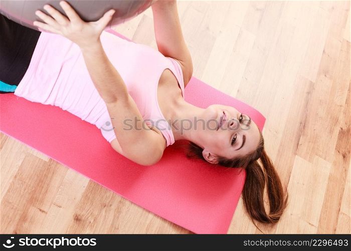 Sport, fitness, people, gym concept. Young lady lying on mat with fit ball. Girl is doing workout. . Young lady lying on mat with fit ball.