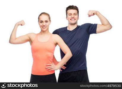 sport, fitness, power, strength and people concept - happy sportive man and woman showing biceps. happy sportive man and woman showing biceps power