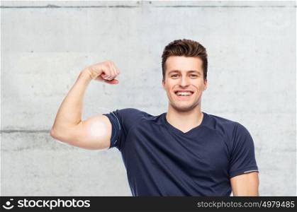 sport, fitness, power, strength and people concept - happy sportive man showing bicep over concrete wall background. sportive man showing bicep power