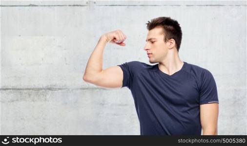 sport, fitness, power, strength and people concept - sportive man showing bicep over concrete wall background. sportive man showing bicep power