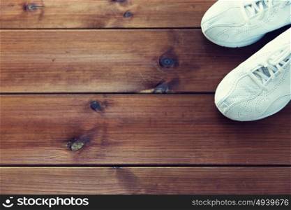 sport, fitness, shoes, footwear and objects concept - close up of sneakers on wooden floor. close up of sneakers on wooden floor