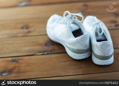 sport, fitness, shoes, footwear and objects concept - close up of sneakers on wooden floor