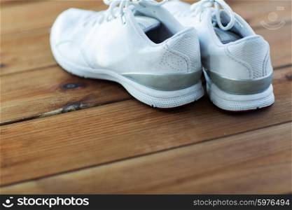 sport, fitness, shoes, footwear and objects concept - close up of sneakers on wooden floor