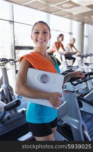 sport, fitness, slimming and people concept - smiling woman with scales and towel in gym