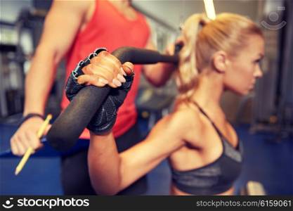 sport, fitness, teamwork and people concept - close up of young woman and personal trainer flexing muscles on cable gym machine