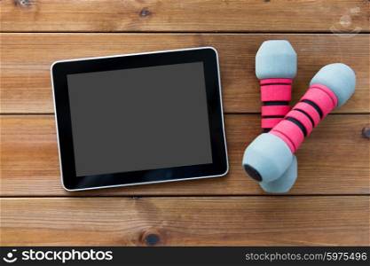 sport, fitness, technology and objects concept - close up of dumbbells and tablet pc computer on wooden floor