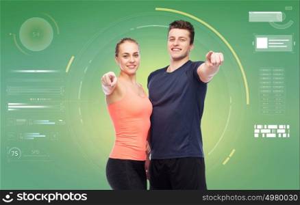 sport, fitness, technology and people concept - happy sportive man and woman pointing finger on you over green background. happy sportive man and woman pointing finger