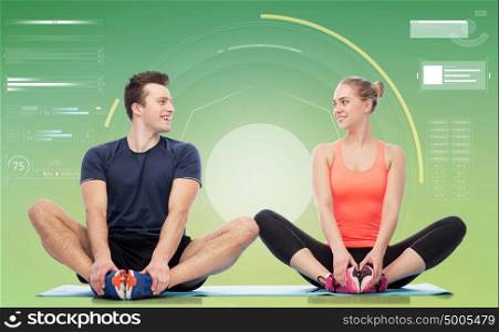 sport, fitness, technology and people concept - happy sportive man and woman sitting on mats over green background. happy sportive man and woman sitting on mats