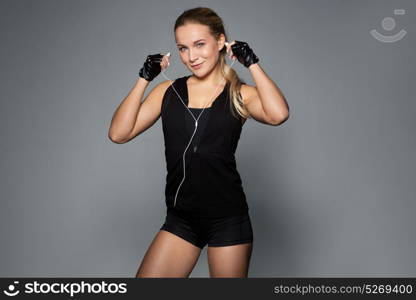 sport, fitness, technology and people concept - young woman with earphones listening to music in gym. woman with earphones listening to music in gym