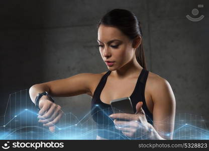 sport, fitness, technology and people concept - young woman with heart-rate watch and smartphone in gym. woman with heart-rate watch and smartphone in gym