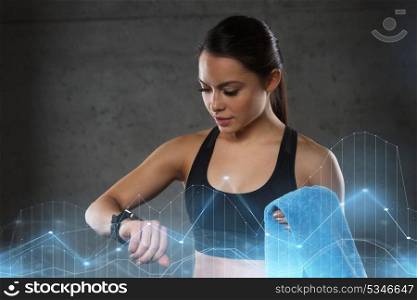 sport, fitness, technology and people concept - young woman with heart-rate watch and towel in gym. young woman with heart-rate watch and towel in gym
