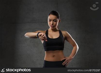 sport, fitness, technology and people concept - young woman with heart-rate watch in gym