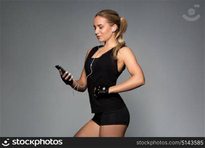 sport, fitness, technology and people concept - young woman with smartphone and earphones listening to music in gym. woman with smartphone and earphones in gym
