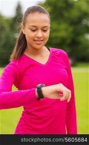 sport, fitness, technology, healthcare and people concept - smiling young woman with heart rate watch outdoors