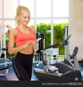 sport, fitness, technology, internet and healthcare concept - smiling sporty woman with smartphone