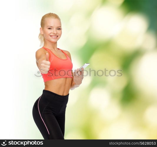 sport, fitness, technology, internet and healthcare concept - smiling sporty woman with smartphone showing thumbs up