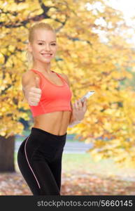 sport, fitness, technology, internet and healthcare concept - smiling sporty woman with smartphone showing thumbs up