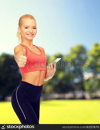 sport, fitness, technology, internet and healthcare concept - smiling sporty woman with smartphone showing thumbs up