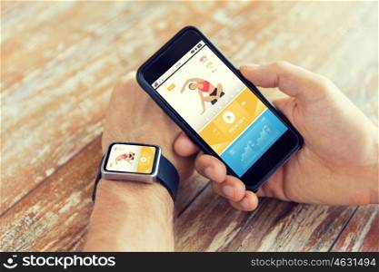 sport, fitness, technology, responsive design and people concept - close up of male hand holding smart phone and wearing watch with sports application on screen
