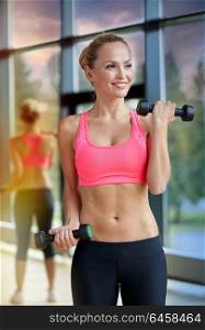 sport, fitness, training, weightlifting and people concept - young sporty woman with dumbbells flexing biceps in gym. young sporty woman with dumbbells flexing biceps