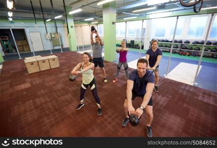 sport, fitness, weightlifting and training concept - group of people with kettlebells and heart-rate trackers exercising in gym. group of people with kettlebells exercising in gym. group of people with kettlebells exercising in gym