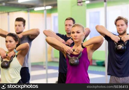 sport, fitness, weightlifting and training concept - group of people with kettlebells exercising in gym. group of people with kettlebells exercising in gym