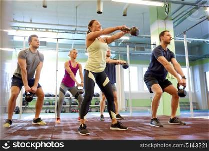sport, fitness, weightlifting and training concept - group of people with kettlebells exercising in gym. group of people with kettlebells exercising in gym
