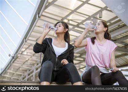 Sport Fitness Women drinking mineral water after running exercise modern city wear wellness sportswear outside. Young woman workout outdoor exercising outside. Healthy wellness lifestyle woman concept