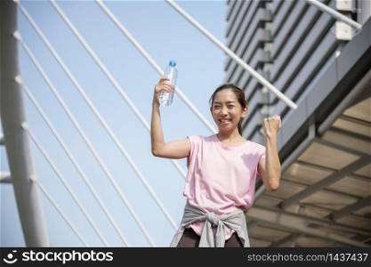 Sport Fitness Women drinking water in modern city wear wellness sportswear outside. Young woman workout outdoor exercising on bright sunny outside. Healthy wellness lifestyle woman concept.