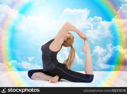 sport, fitness, yoga, people and health concept - happy young woman doing headstand exercise on wooden berth over white clouds and rainbow on blue sky background