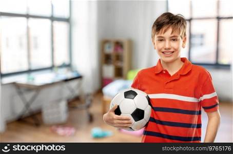 sport, football and leisure games concept - happy smiling boy holding soccer ball over home room background. happy smiling boy holding soccer ball at home