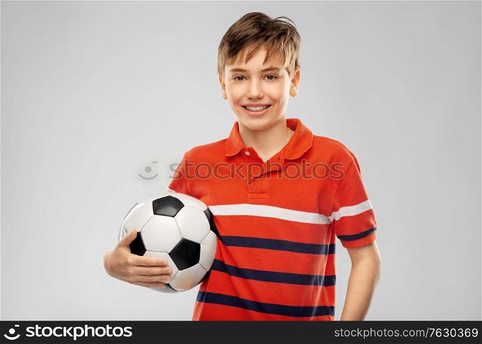 sport, football and leisure games concept - happy smiling boy holding soccer ball over grey background. happy smiling boy holding soccer ball