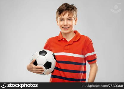 sport, football and leisure games concept - happy smiling boy holding soccer ball over grey background. happy smiling boy holding soccer ball