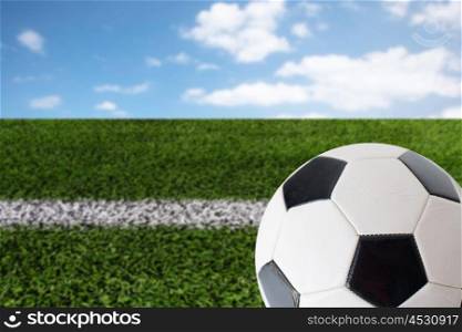 sport, football and sports equipment concept - close up of soccer ball over playing field and blue sky background