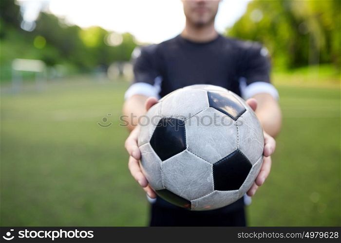 sport, football training and people - soccer player hands holding ball on field. soccer player with ball on football field