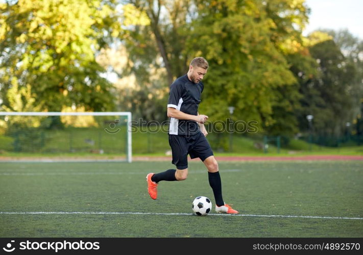 sport, football training and people - soccer player playing with ball on field