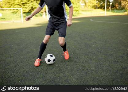 sport, football training and people - soccer player playing with ball on field