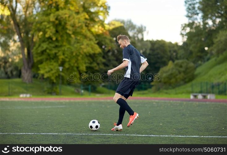 sport, football training and people - soccer player playing with ball on field. soccer player playing with ball on football field