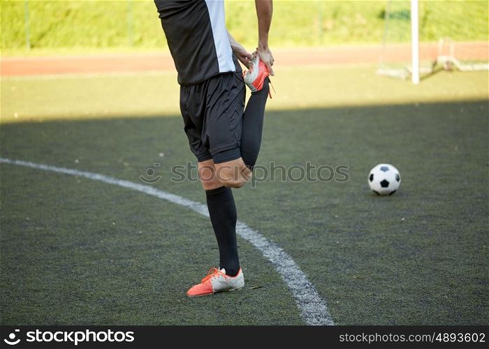 sport, football training and people - soccer player stretching leg on field