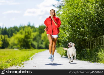 Sport girl. Young attractive sport girl running with dog in park